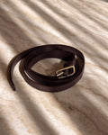 Brown leather belt with a silver buckle on a textured beige surface